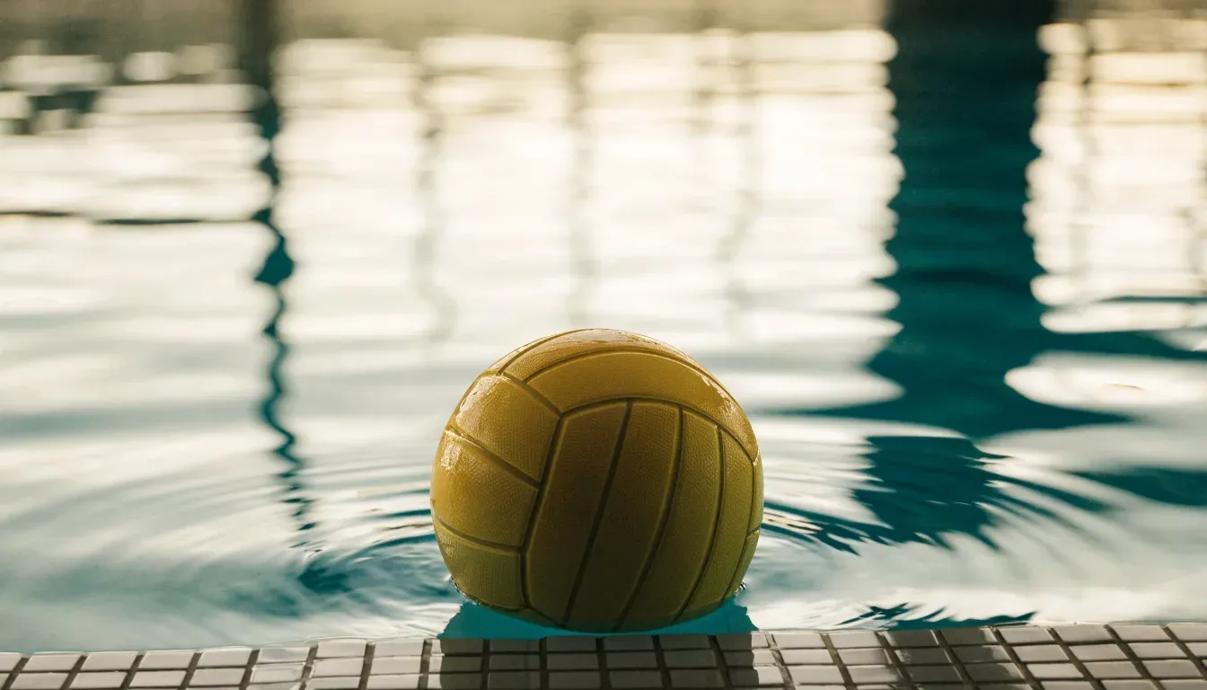 Ein gelber Ball treibt auf ruhigem türkisfarbenem Beckenwasser, feine Wellen im weichen Licht.